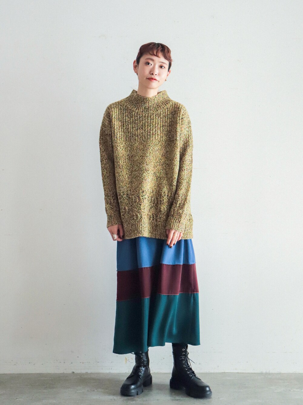 イエロー系のニット/セーター、ブルー系のスカートを着用したレディースの冬コーディネートの1枚目の写真
