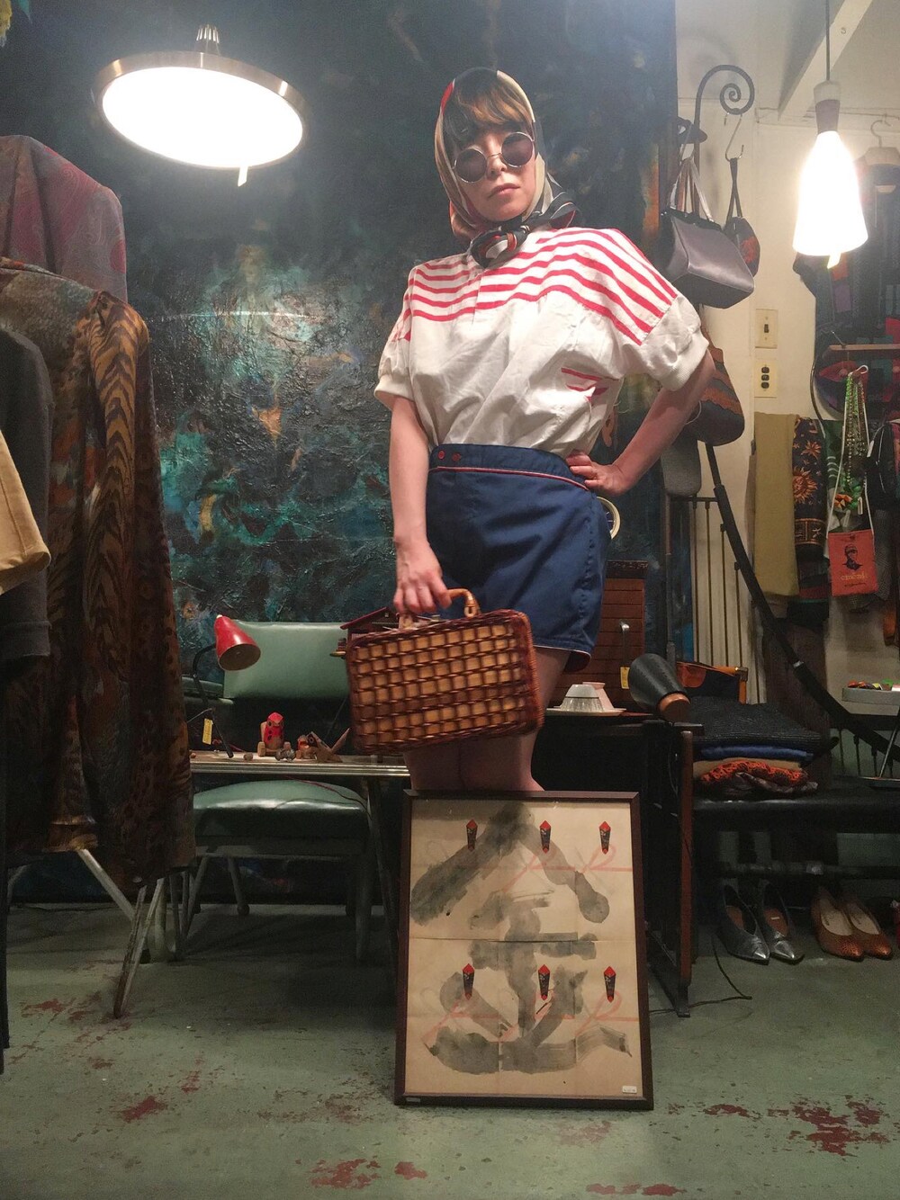 ホワイト系のトップス、ブルー系のパンツ、ブラウン系のかごバッグを着用したレディースの夏コーディネートの1枚目の写真