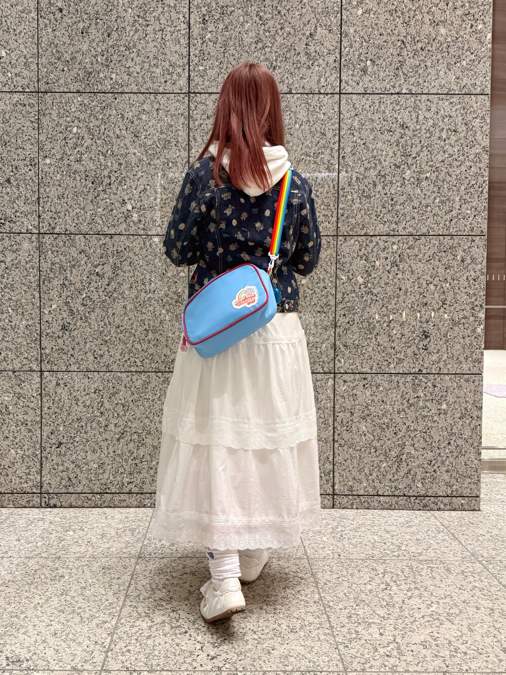 ブルー系のデニムジャケット、ブルー系のショルダーバッグ、ホワイト系のスカートを着用したレディースの春コーディネートの1枚目の写真