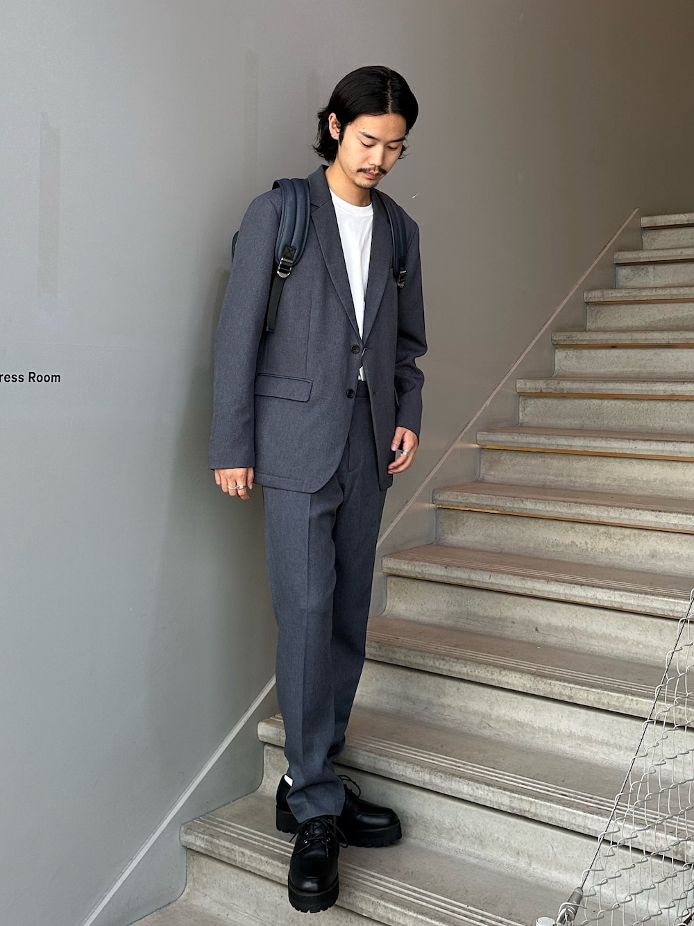 グレー系のセットアップ、ブルー系のバックパック/リュック、ブラック系のその他シューズを着用したメンズの夏コーディネートの1枚目の写真