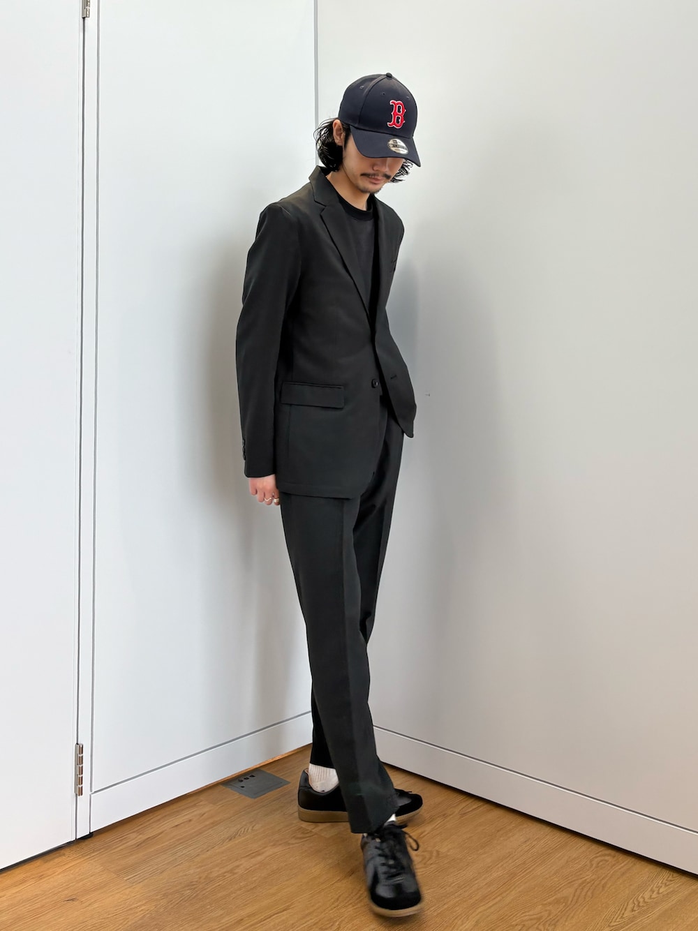 ブラック系のセットアップ、ブラック系のスニーカーを着用したメンズの春コーディネートの1枚目の写真