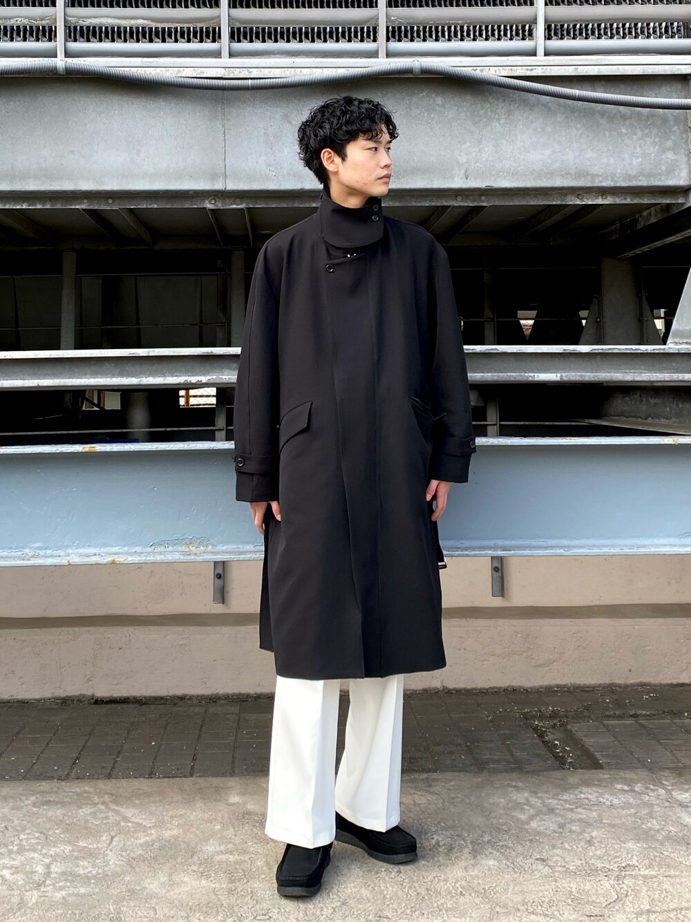 ブラック系のステンカラーコート、ホワイト系のその他パンツを着用したメンズの冬コーディネートの1枚目の写真