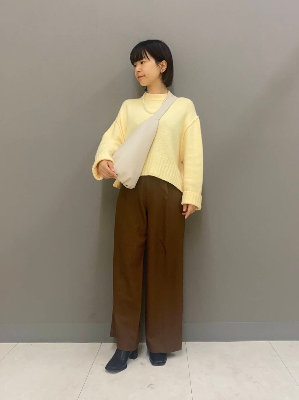 ブラック系のブーツ、ブラウン系のその他パンツ、ホワイト系のショルダーバッグを着用したレディースの冬コーディネートの1枚目の写真