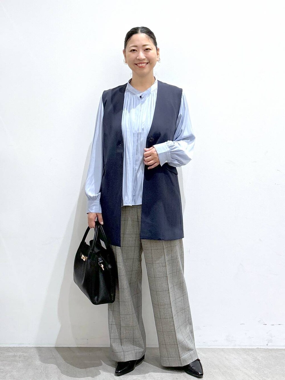 ブルー系のベスト、ブラック系のハンドバッグ、ブルー系のシャツ/ブラウスを着用したレディースの秋コーディネートの1枚目の写真