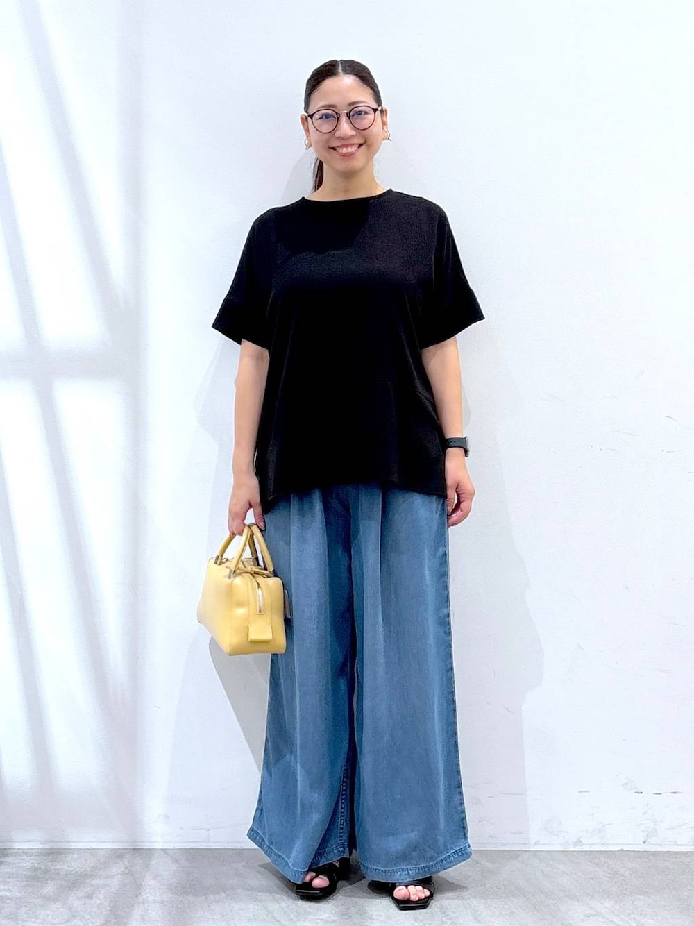 ブラック系のシャツ/ブラウス、ブラック系のサンダル、ブルー系のデニムパンツを着用したレディースの夏コーディネートの1枚目の写真