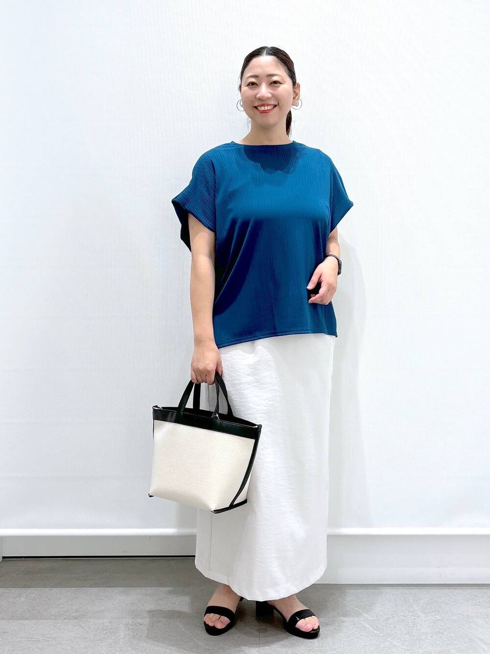 ブルー系のTシャツ/カットソー、グレー系のスカート、ブラック系のトートバッグを着用したレディースの夏コーディネートの1枚目の写真