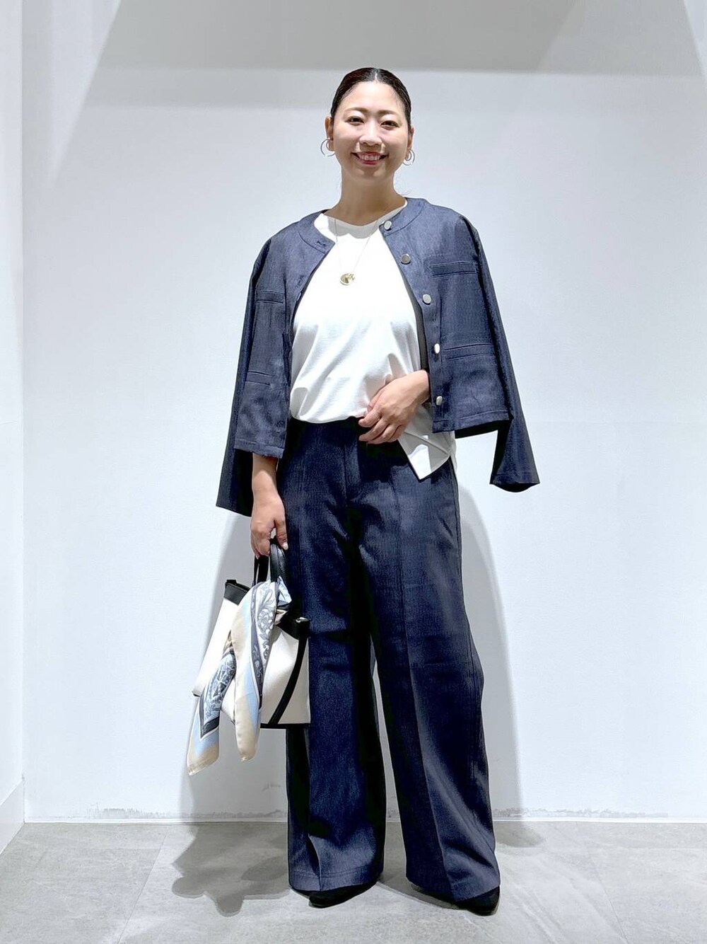 ブラック系のトートバッグ、ブラック系のパンプス、ブルー系のデニムパンツを着用したレディースの秋コーディネートの1枚目の写真