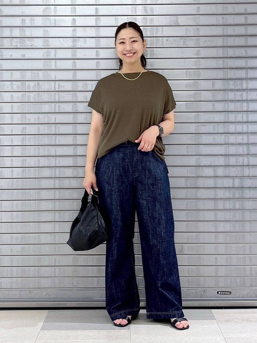 ブルー系のデニムパンツ、ブラック系のハンドバッグ、グリーン系のTシャツ/カットソーを着用したレディースの春コーディネートの1枚目の写真
