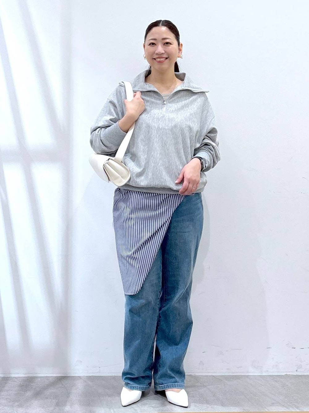ホワイト系のハンドバッグ、ブルー系のデニムパンツ、グレー系のTシャツ/カットソーを着用したレディースの春コーディネートの1枚目の写真