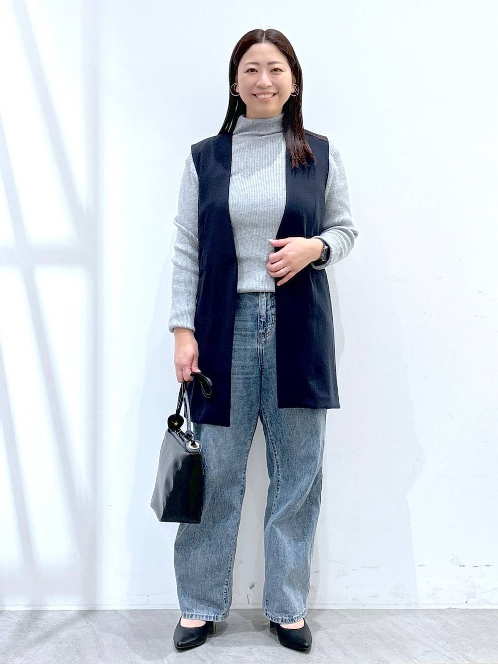 ブルー系のデニムパンツ、グレー系のニット/セーター、ブルー系のスーツベストを着用したレディースの冬コーディネートの1枚目の写真