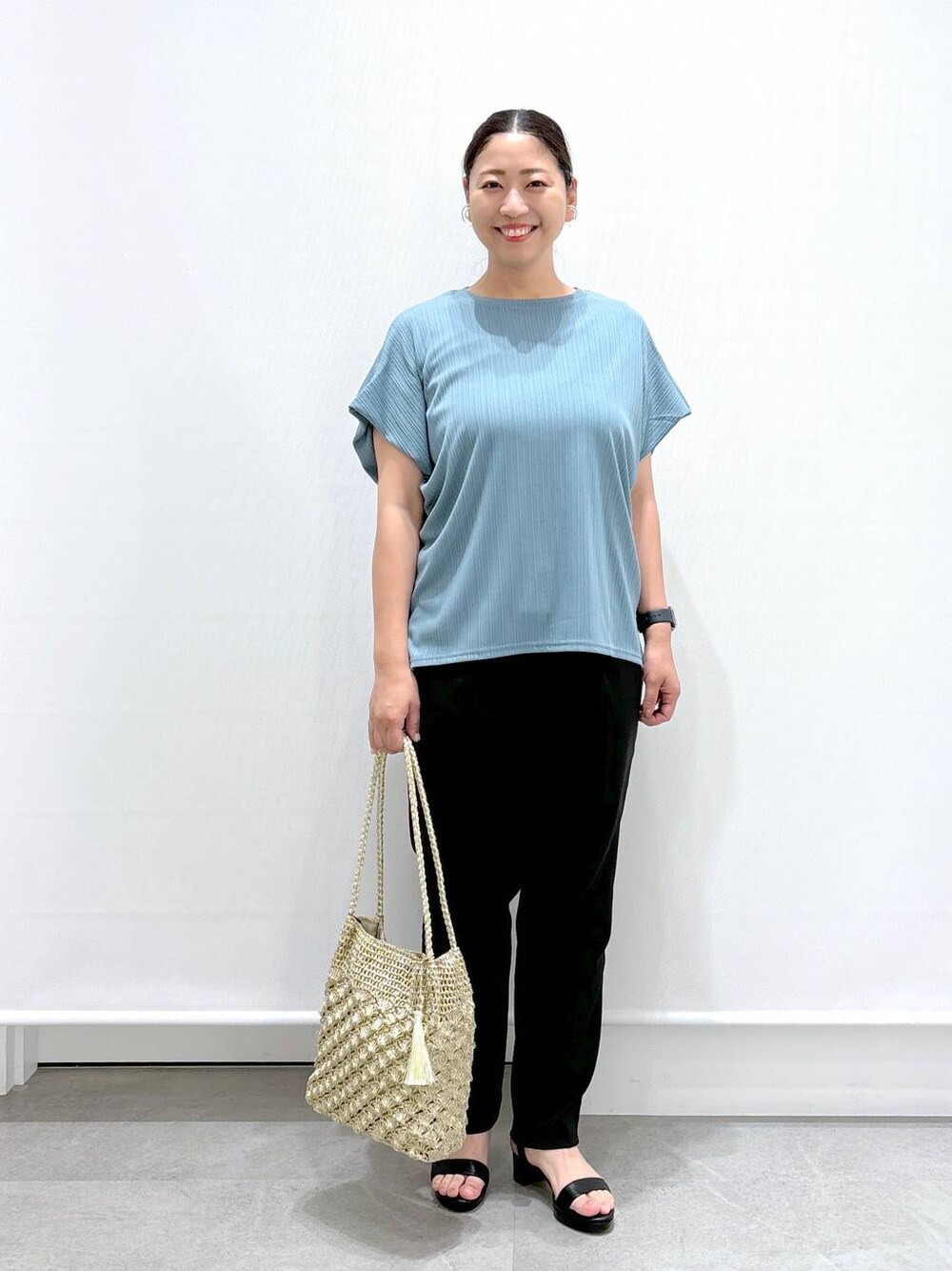 ゴールド系のトートバッグ、ブラック系のその他パンツ、グリーン系のTシャツ/カットソーを着用したレディースの秋コーディネートの1枚目の写真