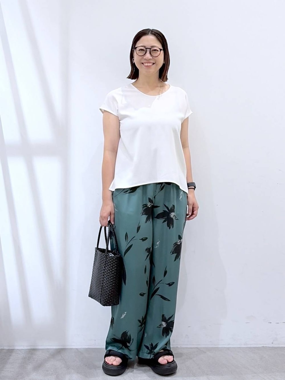 グリーン系のその他パンツ、ブラック系のかごバッグ、ホワイト系のシャツ/ブラウスを着用したレディースの夏コーディネートの1枚目の写真