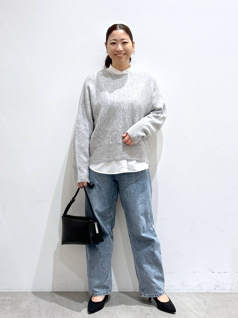 ブルー系のデニムパンツ、ホワイト系のシャツ/ブラウス、グレー系のニット/セーターを着用したレディースの冬コーディネートの1枚目の写真