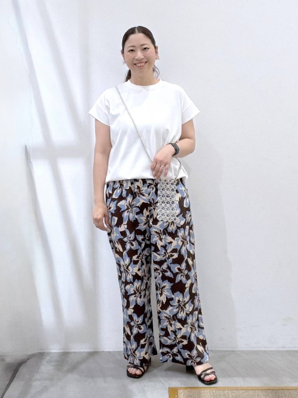 ブルー系のその他パンツ、ブラック系のサンダル、ホワイト系のTシャツ/カットソーを着用したレディースの夏コーディネートの1枚目の写真