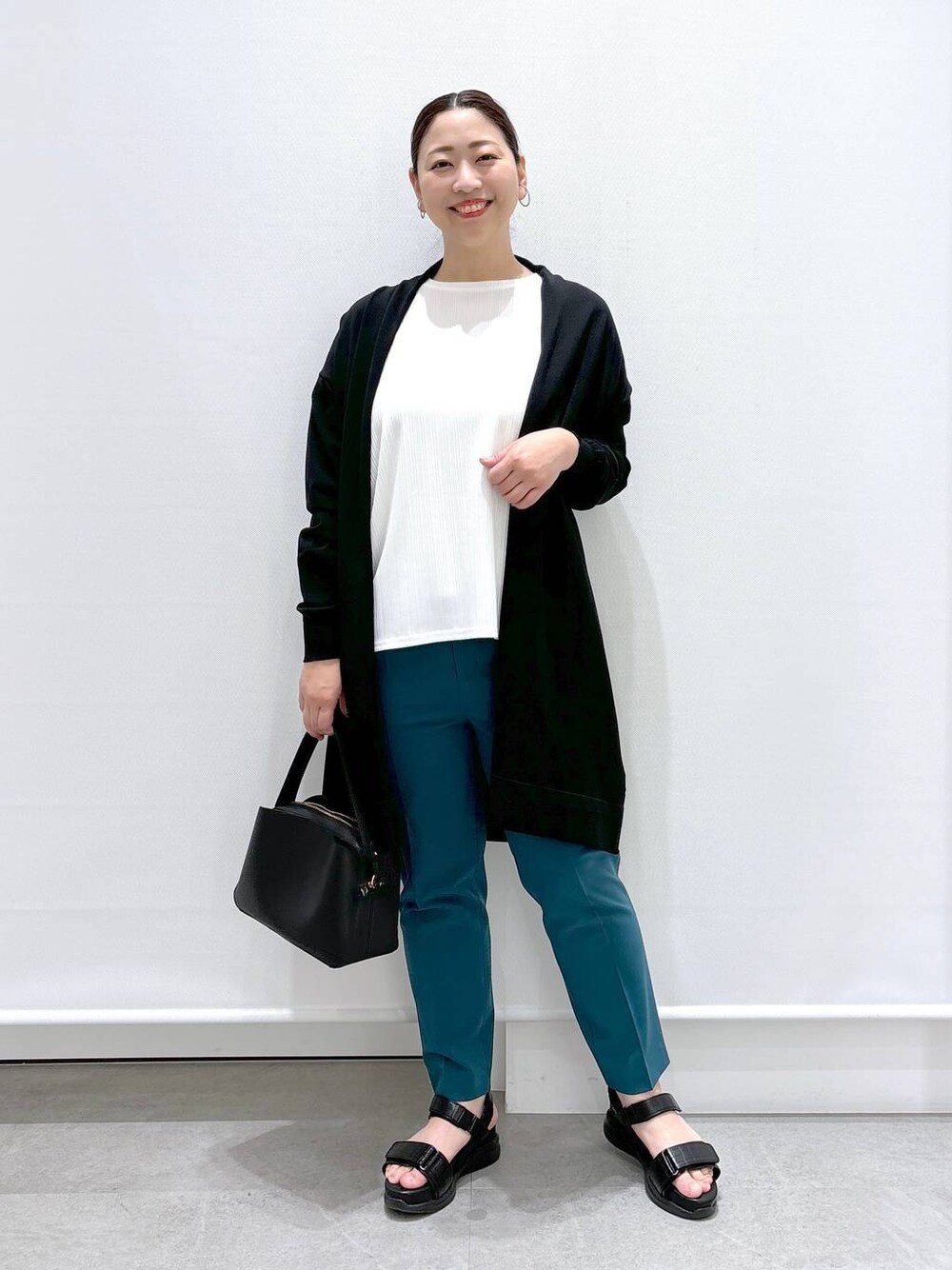 グリーン系のその他パンツ、ブラック系のハンドバッグ、ブラック系のサンダルを着用したレディースの春コーディネートの1枚目の写真
