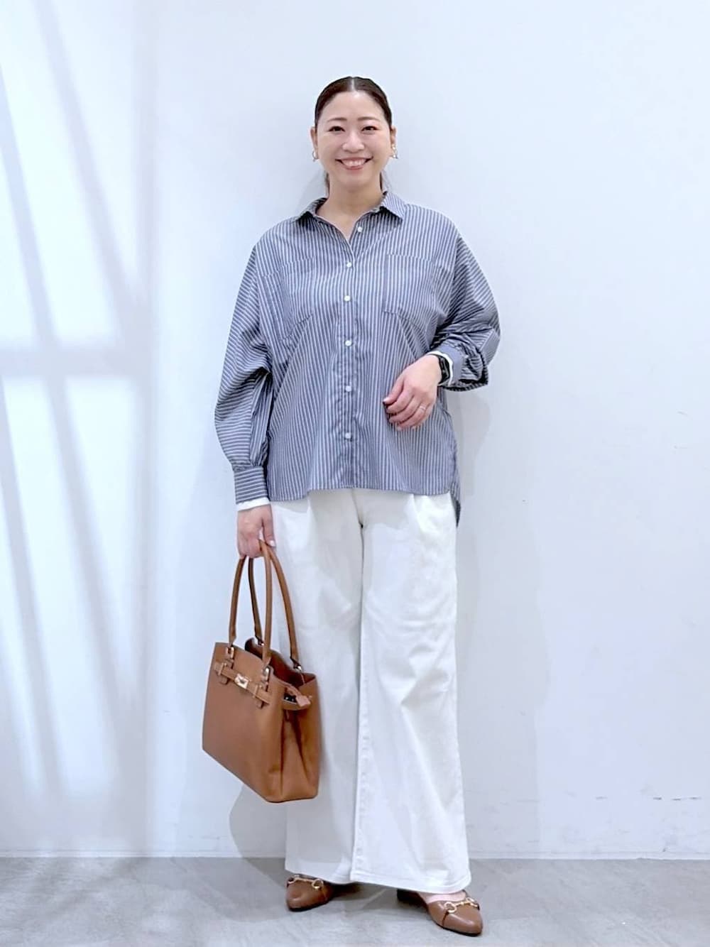 ホワイト系のデニムパンツ、イエロー系のハンドバッグ、ブルー系のシャツ/ブラウスを着用したレディースの春コーディネートの1枚目の写真