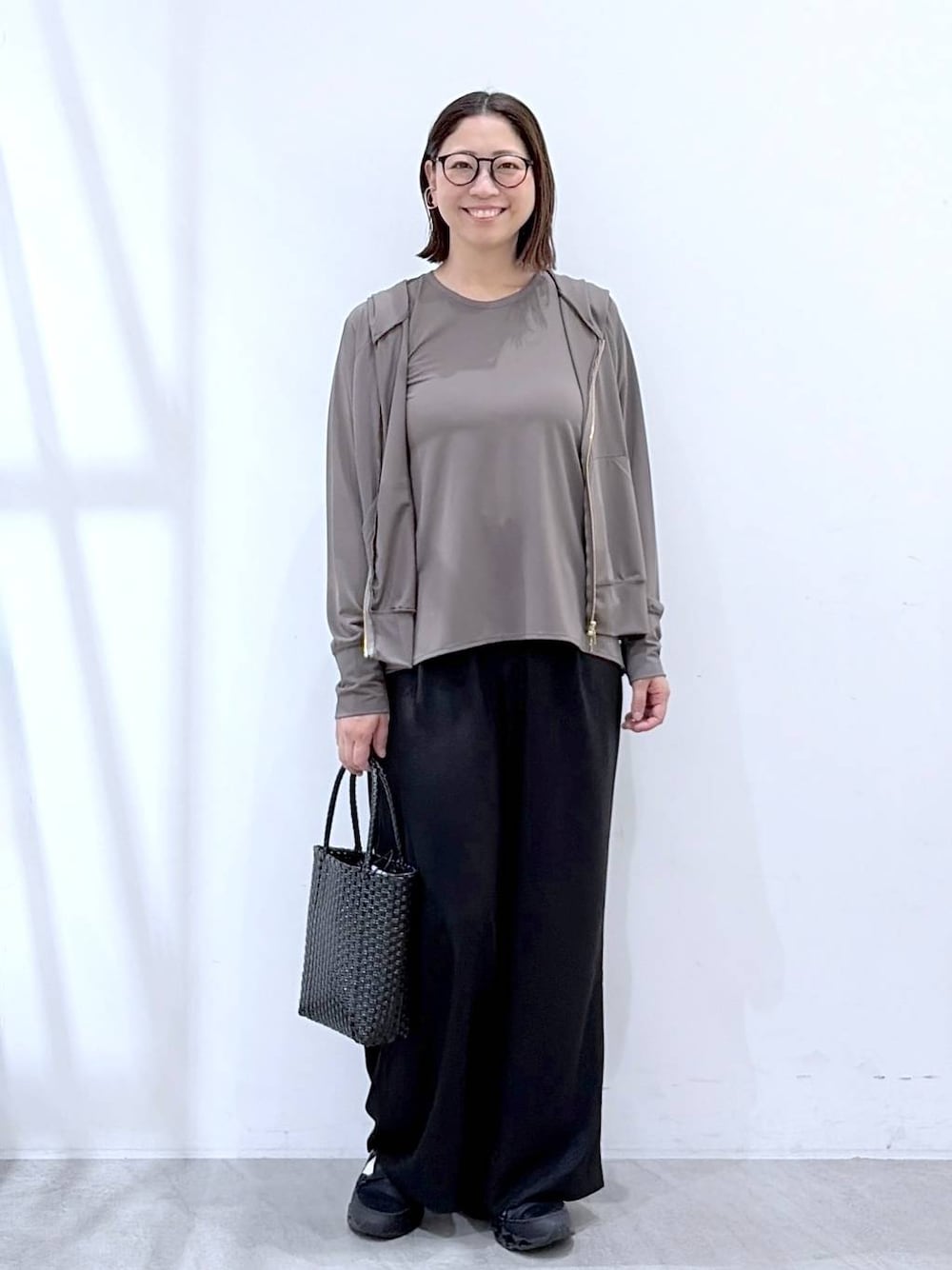 ブラック系のその他パンツ、ブラック系のかごバッグ、グレー系のパーカーを着用したレディースの夏コーディネートの1枚目の写真