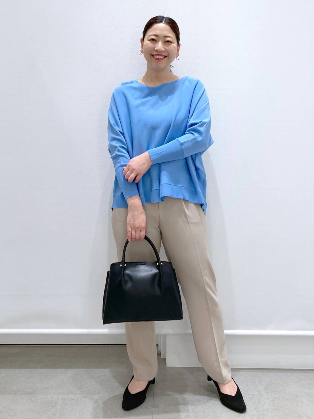 ブラック系のショルダーバッグ、ブルー系のニット/セーター、ベージュ系のその他パンツを着用したレディースの春コーディネートの1枚目の写真