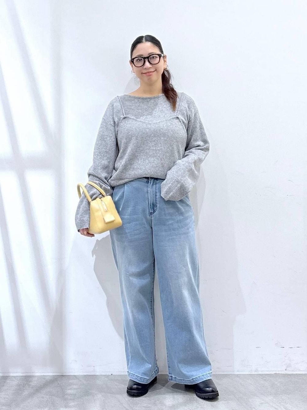 ブラック系のブーツ、ブルー系のデニムパンツ、グレー系のニット/セーターを着用したレディースの冬コーディネートの1枚目の写真