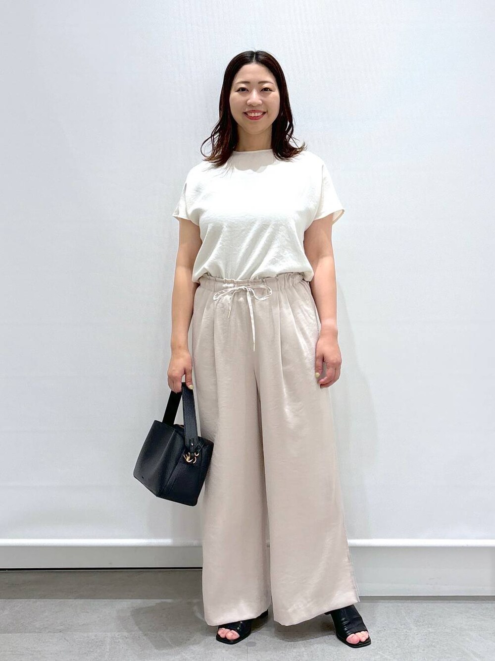 ブラック系のサンダル、ブラック系のハンドバッグ、ベージュ系のその他パンツを着用したレディースの夏コーディネートの1枚目の写真