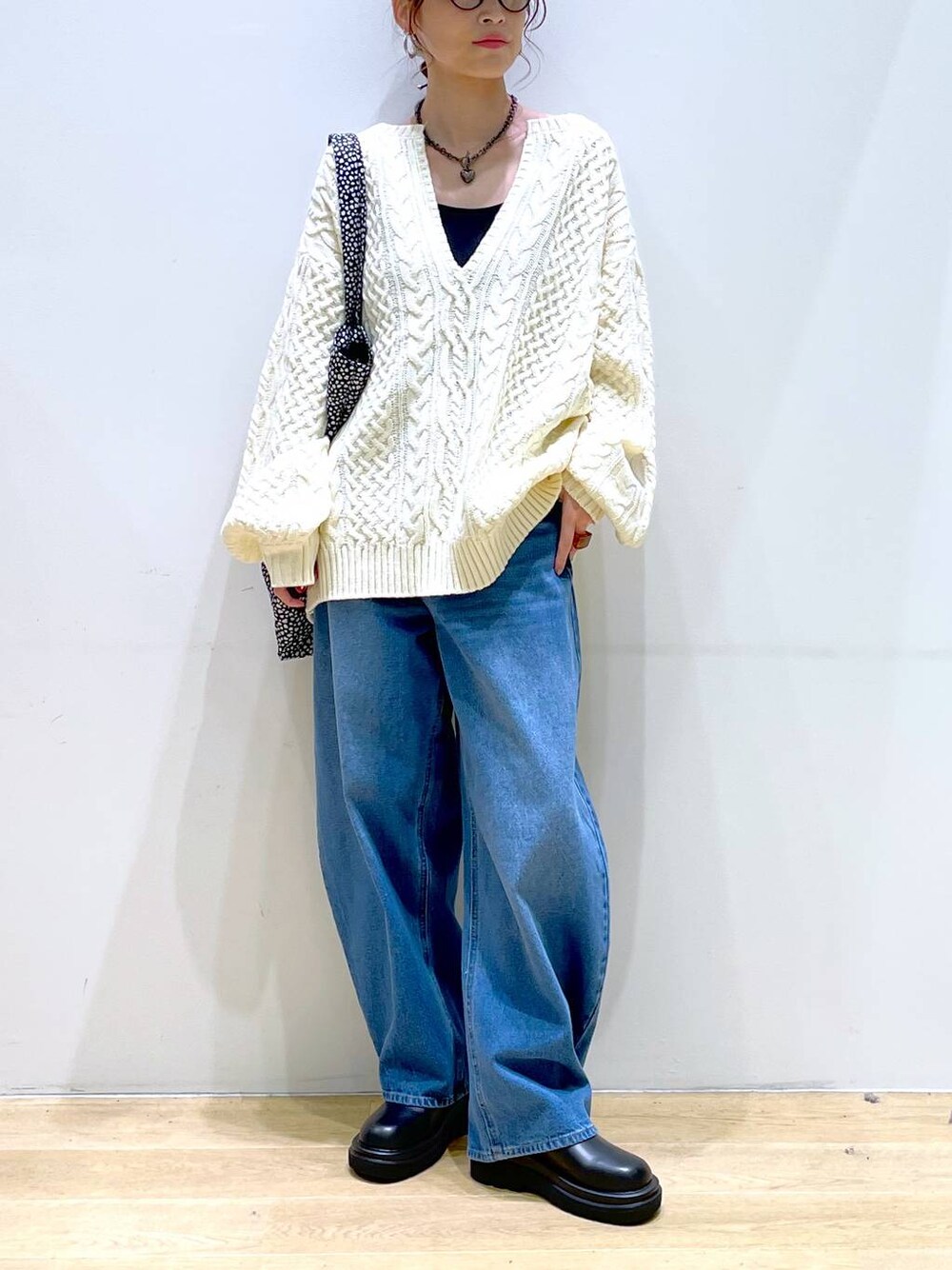 ブルー系のデニムパンツ、ブラック系のブーツ、ホワイト系のニット/セーターを着用したレディースの冬コーディネートの1枚目の写真