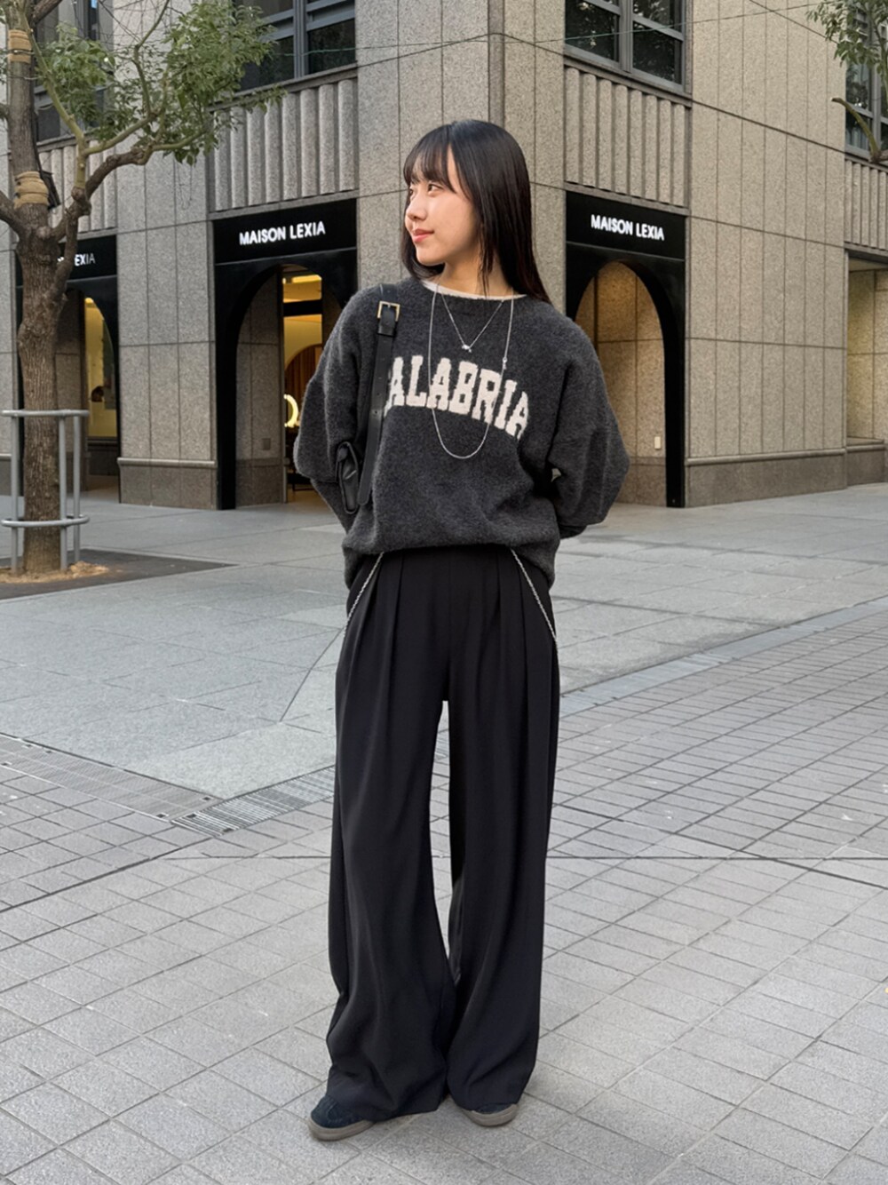 ブラック系のスラックス、グレー系のニット/セーター、ホワイト系のTシャツ/カットソーを着用したレディースの冬コーディネートの1枚目の写真