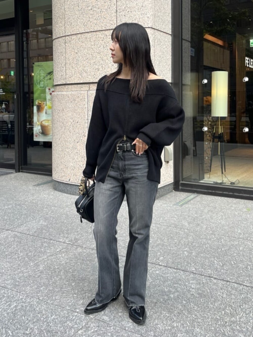 ブラック系のデニムパンツ、ブラック系のニット/セーター、ブラック系のショルダーバッグを着用したレディースの秋コーディネートの1枚目の写真