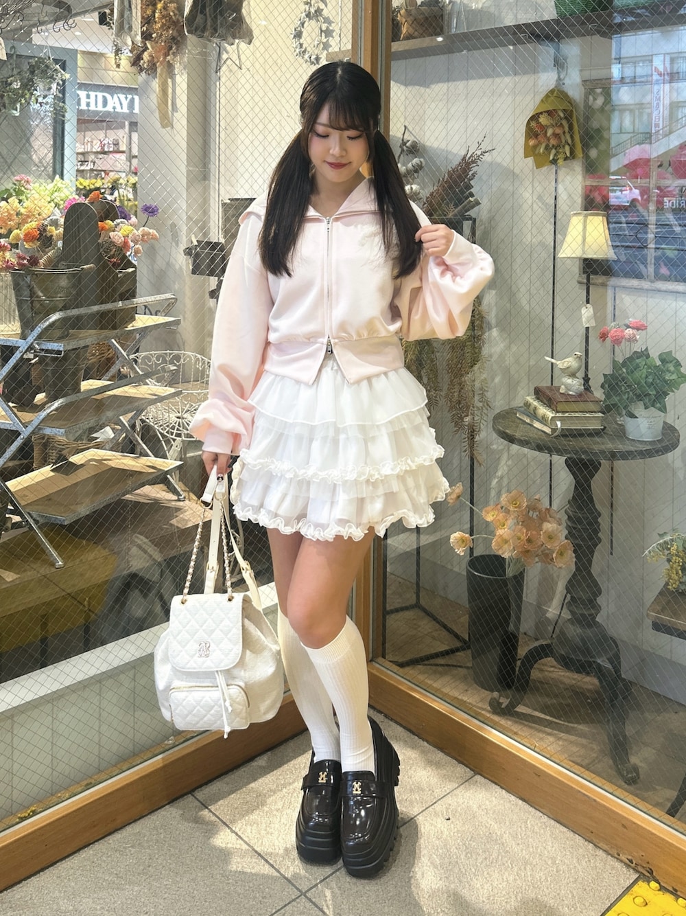 ピンク系のパーカー、ホワイト系のスカート、ホワイト系のバックパック/リュックを着用したレディースの春コーディネートの1枚目の写真