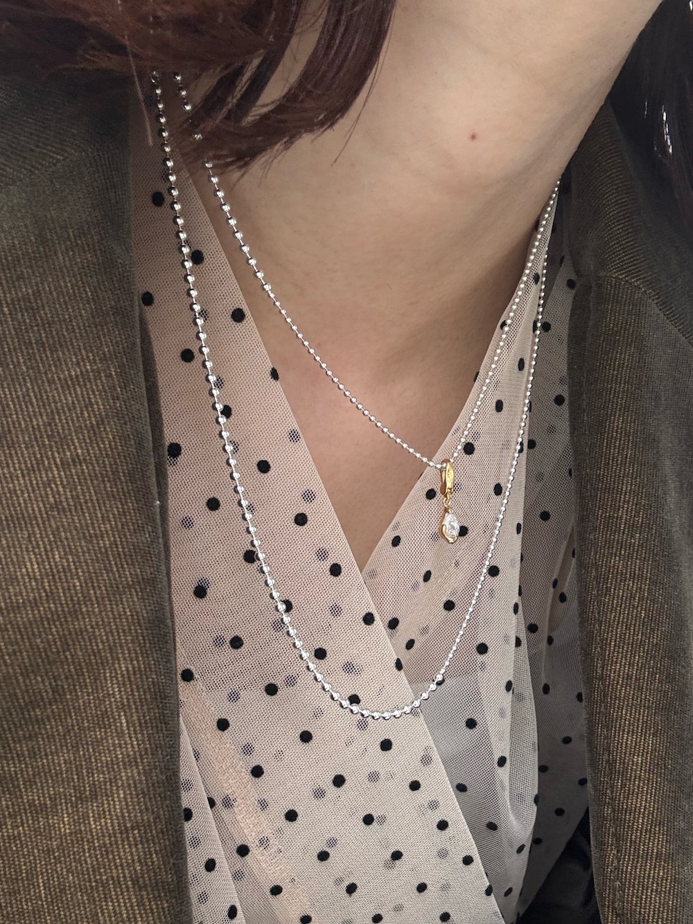 シルバー系のネックレス、シルバー系のネックレス、ゴールド系のチャームを着用したレディースの春コーディネートの1枚目の写真