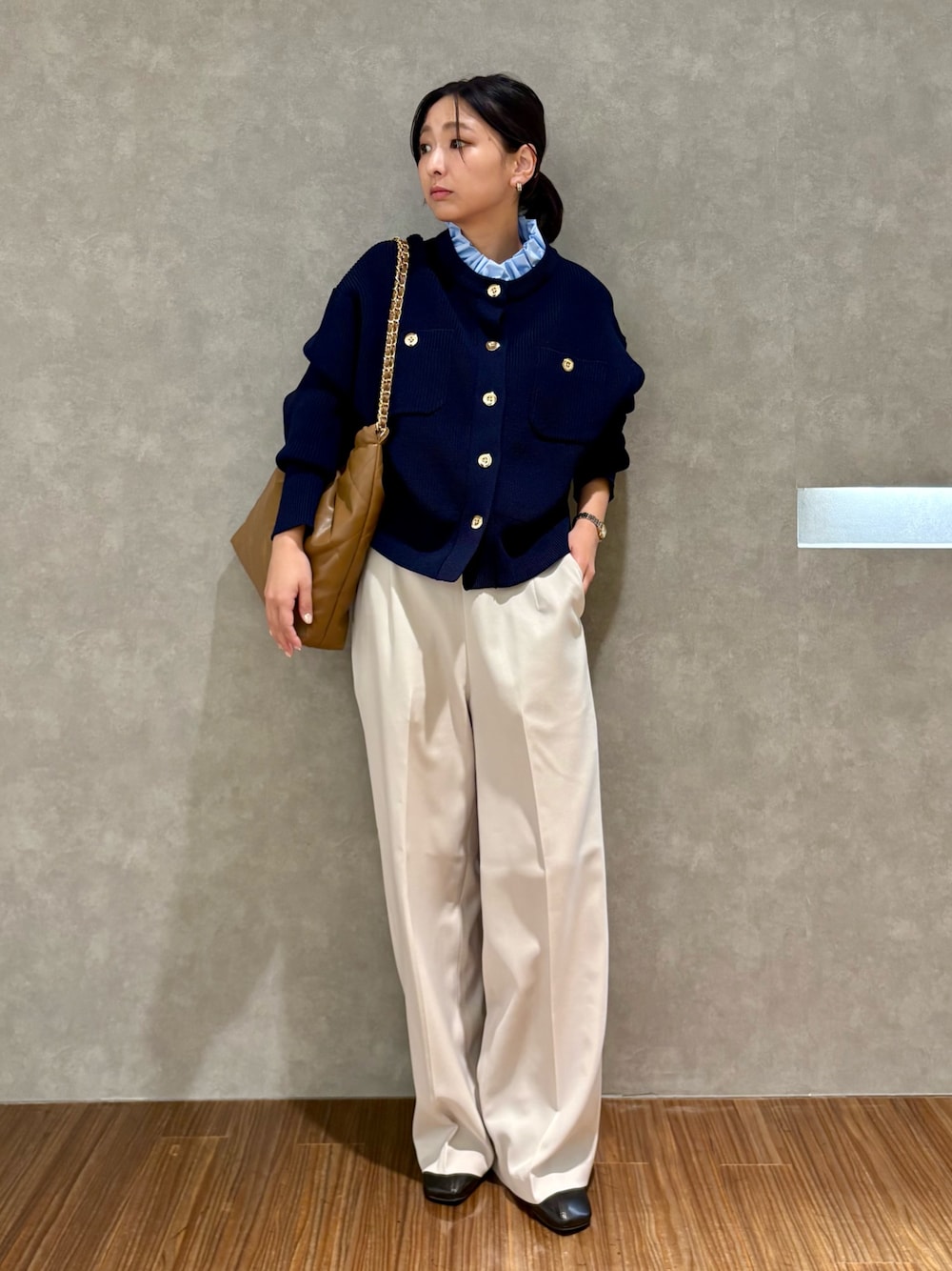 ブルー系のカーディガン/ボレロ、ベージュ系のその他パンツ、ブラウン系のハンドバッグを着用したレディースの冬コーディネートの1枚目の写真