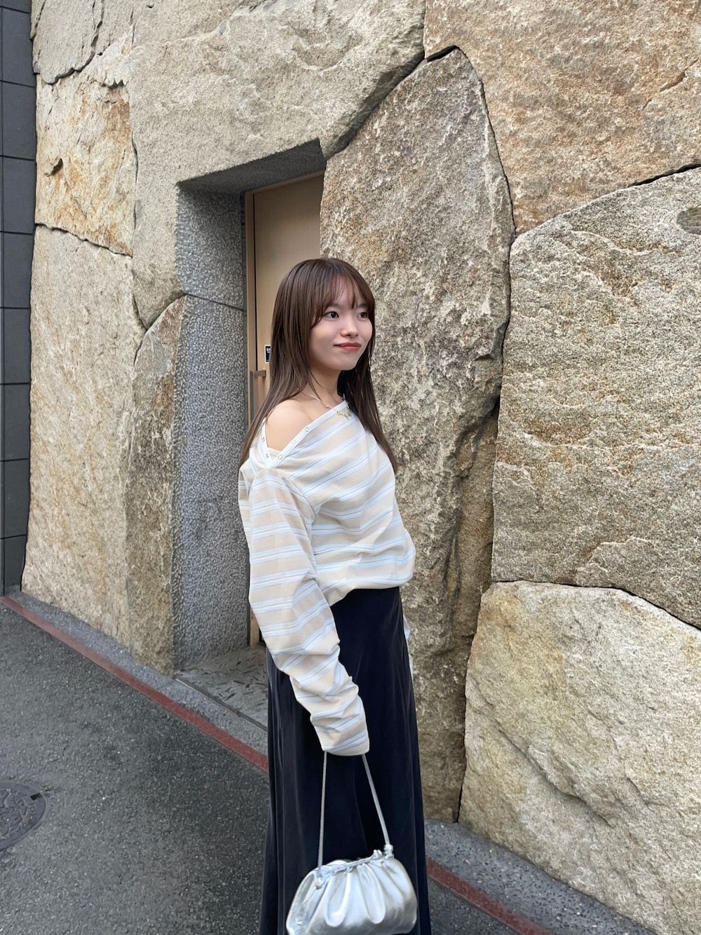 ベージュ系のTシャツ/カットソー、ブラック系のスカート、シルバー系のショルダーバッグを着用したレディースの春コーディネートの1枚目の写真