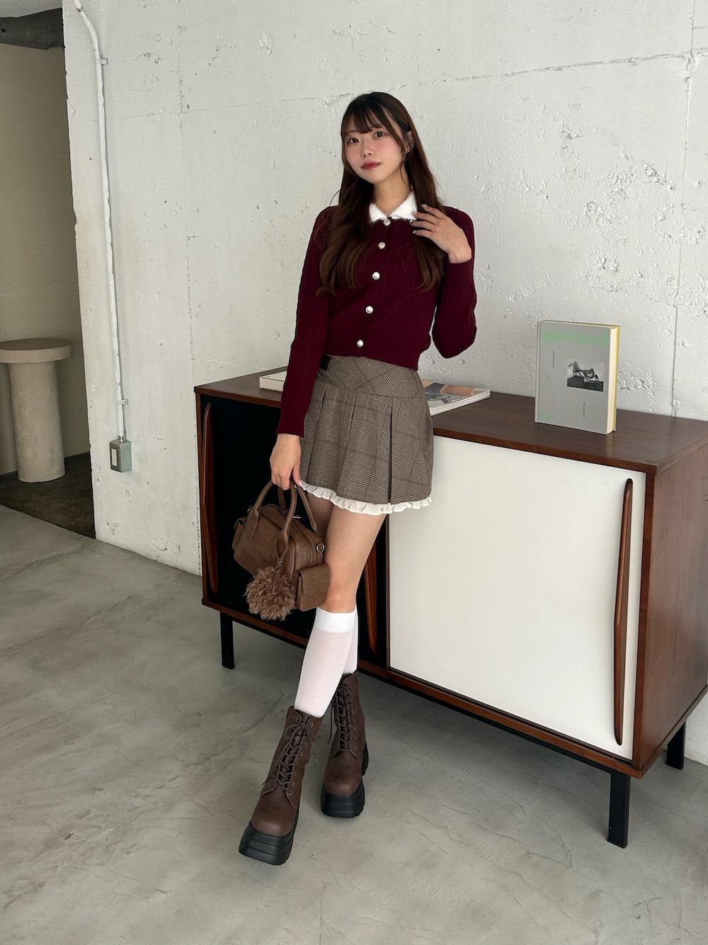 ブラウン系のスカート、ブラウン系のショルダーバッグ、レッド系のカーディガン/ボレロを着用したレディースの秋コーディネートの1枚目の写真