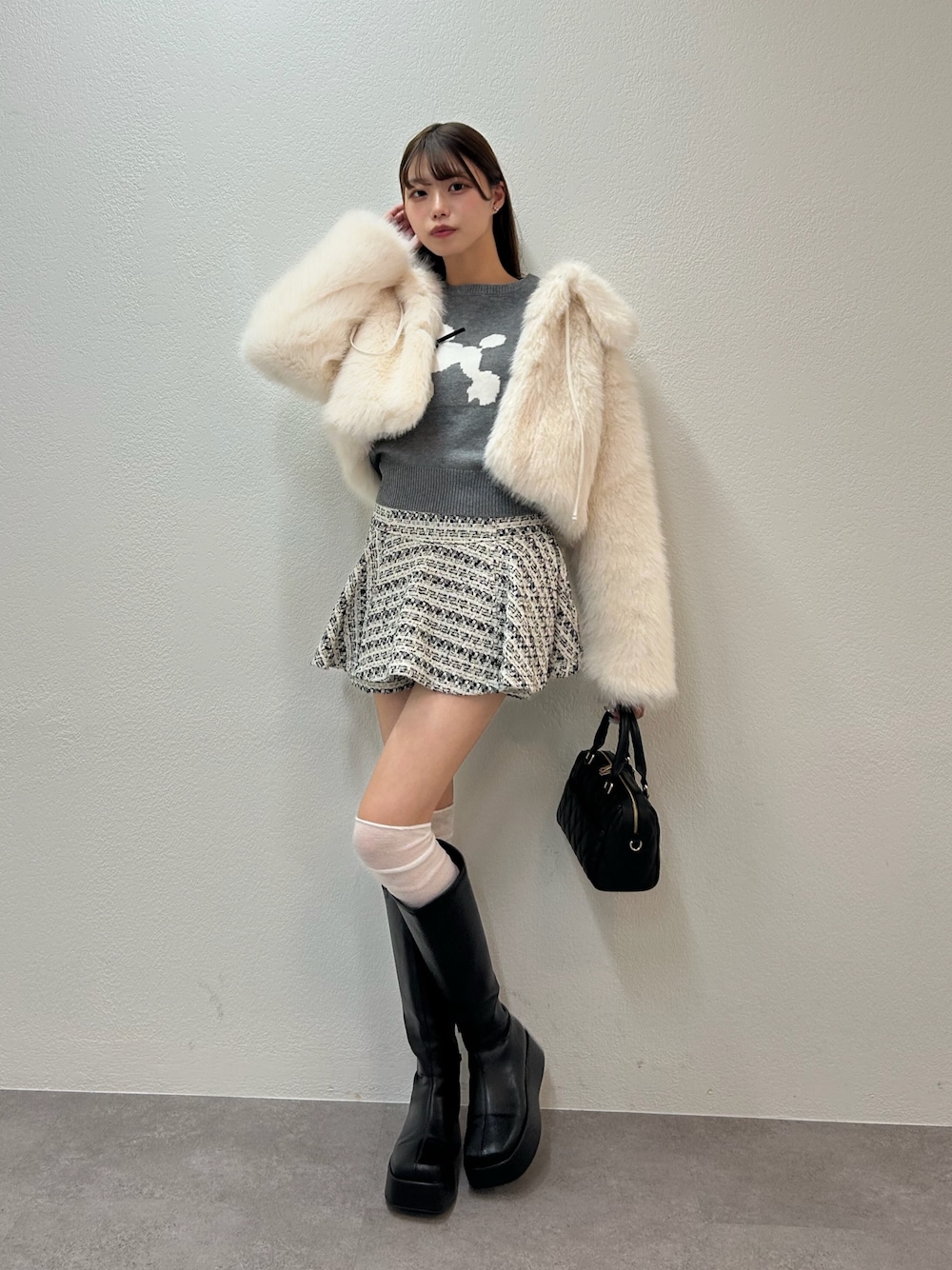 グレー系のニット/セーター、ホワイト系のブルゾン、ブラック系のボストンバッグを着用したレディースの秋コーディネートの1枚目の写真