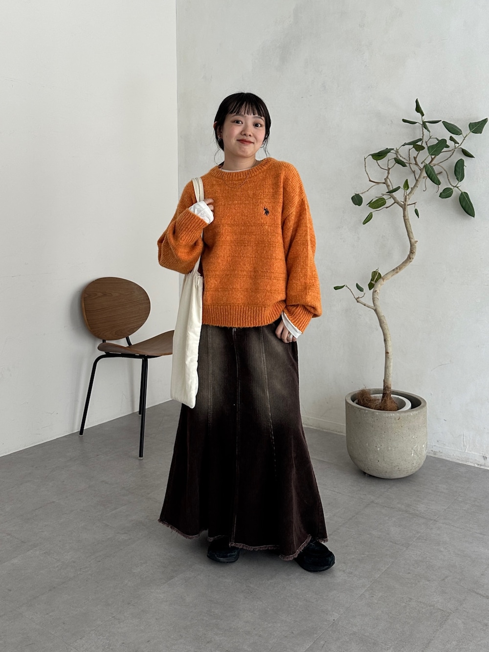 ホワイト系のTシャツ/カットソー、ホワイト系のトートバッグ、オレンジ系のニット/セーターを着用したレディースの秋コーディネートの1枚目の写真