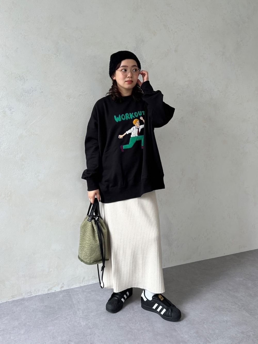 ブラック系のスウェット、ベージュ系のスカート、ブラック系のスニーカーを着用したレディースの冬コーディネートの1枚目の写真