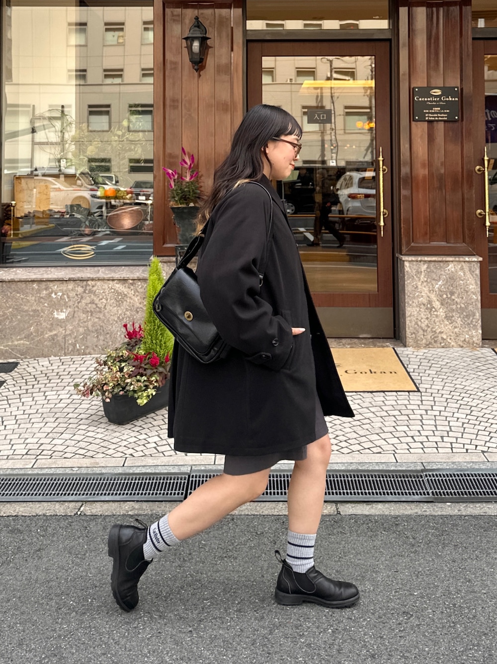 ブラック系のその他アウター、ブラック系のトートバッグ、グレー系のチノパンツを着用したレディースの秋コーディネートの1枚目の写真