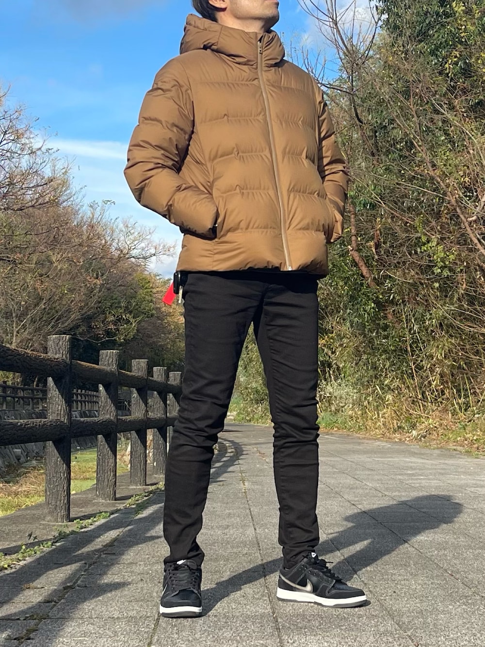 ブラウン系のダウンジャケット/コート、ブラック系のデニムパンツ、ブラック系のスニーカーを着用したメンズの冬コーディネートの1枚目の写真