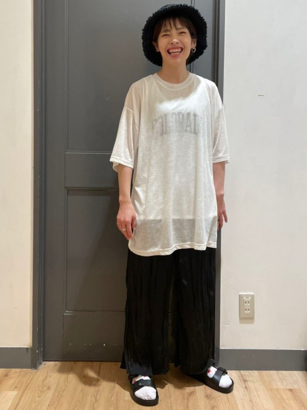 ホワイト系のトップス、ブラック系のパンツ、ブラック系の帽子を着用したレディースの夏コーディネートの1枚目の写真