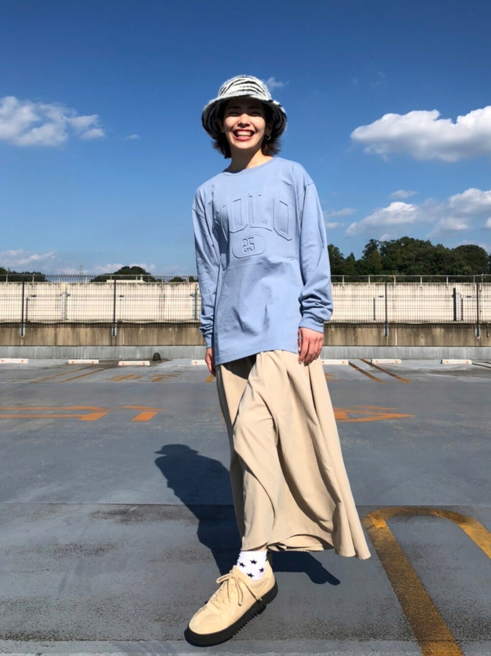 ブルー系のTシャツ/カットソー、ベージュ系のスカート、ブラック系のハットを着用したレディースの秋コーディネートの1枚目の写真