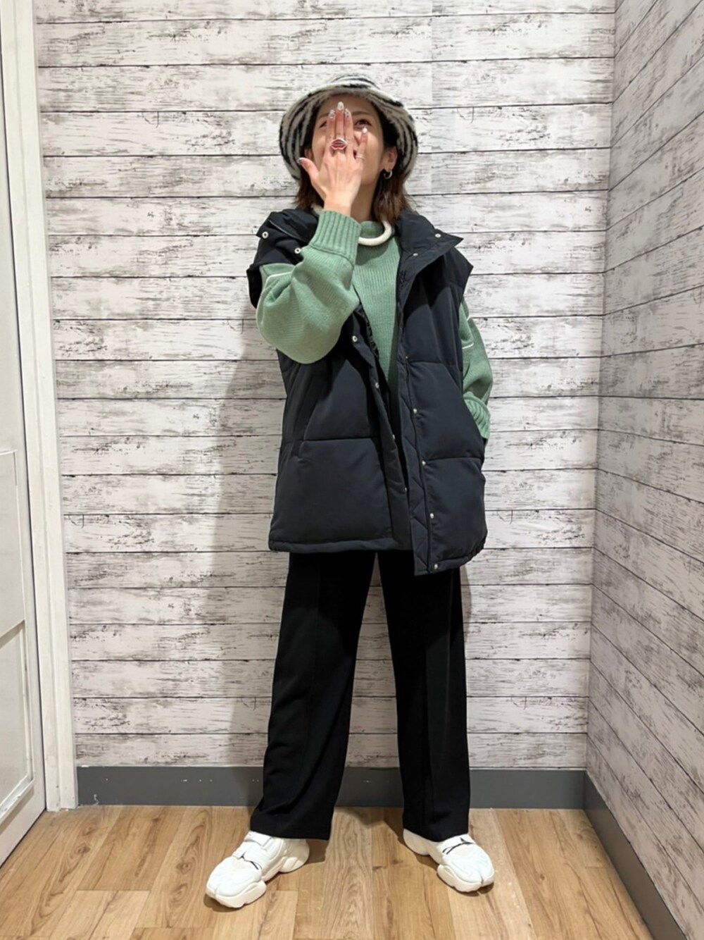 ブラック系のベスト、グリーン系のニット/セーター、ブラック系のその他パンツを着用したレディースの秋コーディネートの1枚目の写真