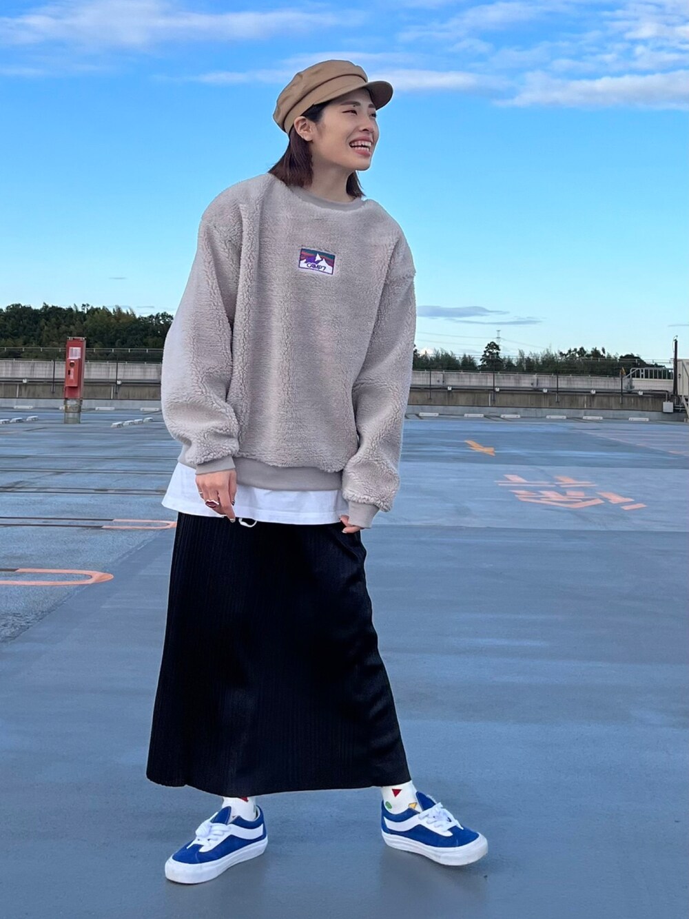 グレー系のスウェット、ブラック系のスカート、ベージュ系のキャスケットを着用したレディースの秋コーディネートの1枚目の写真