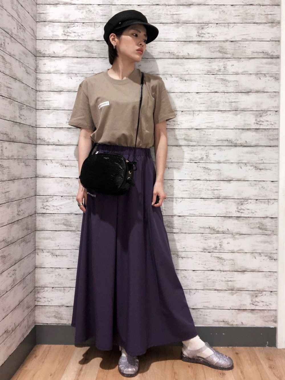 ベージュ系のTシャツ/カットソー、パープル系のスカート、ブラック系のキャスケットを着用したレディースの夏コーディネートの1枚目の写真