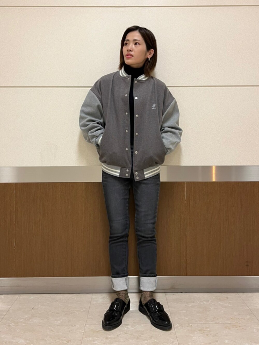 ブラック系のニット/セーター、グレー系のスタジャン、ブラック系のデニムパンツを着用したレディースの秋コーディネートの1枚目の写真