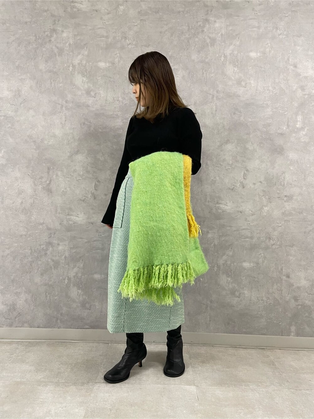 ブラック系のニット/セーター、その他のスカート、グリーン系のストール/ショールを着用したレディースの秋コーディネートの1枚目の写真