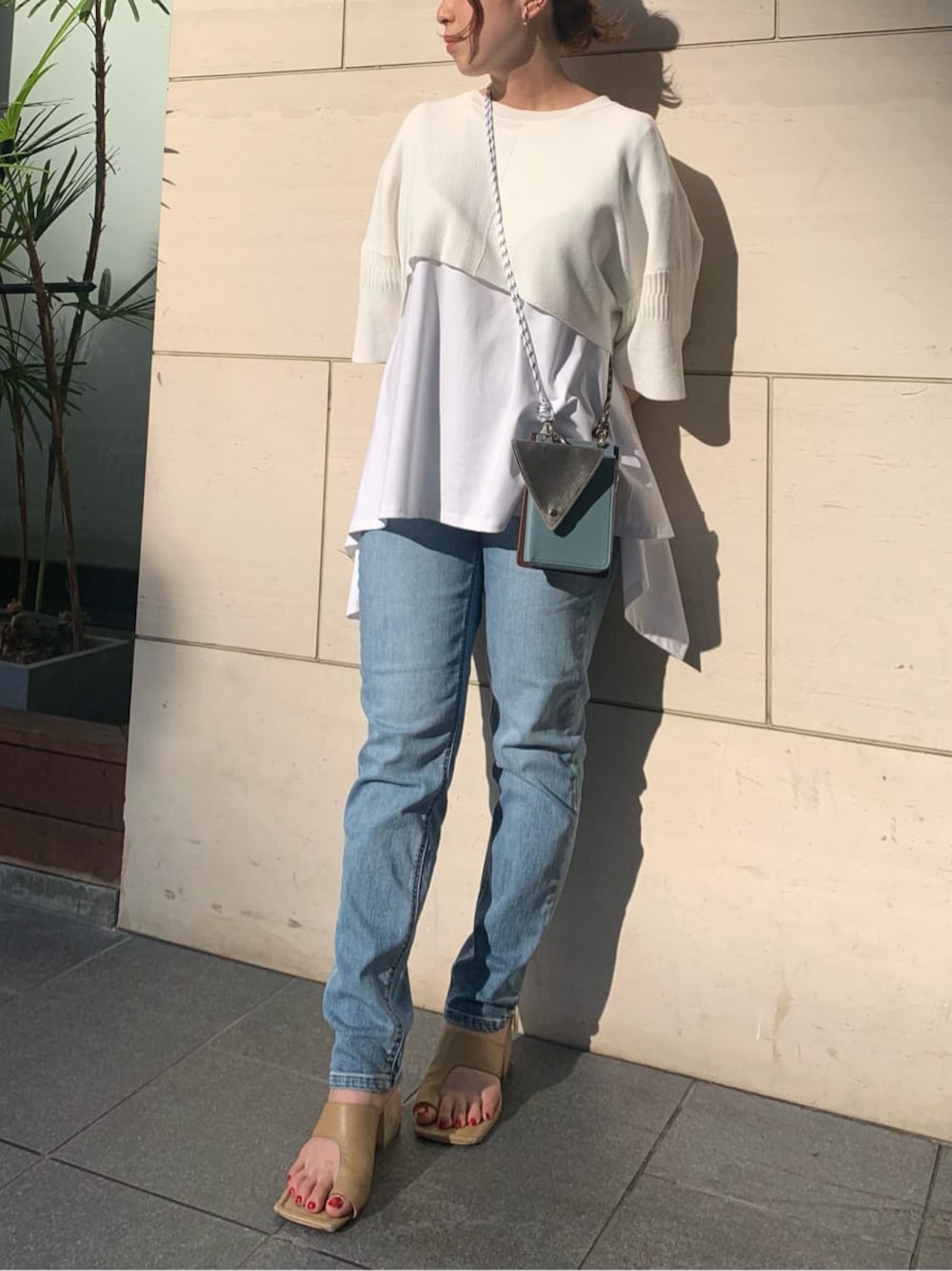 ブルー系のデニムパンツ、ホワイト系のTシャツ/カットソー、ベージュ系のサンダルを着用したレディースの夏コーディネートの1枚目の写真