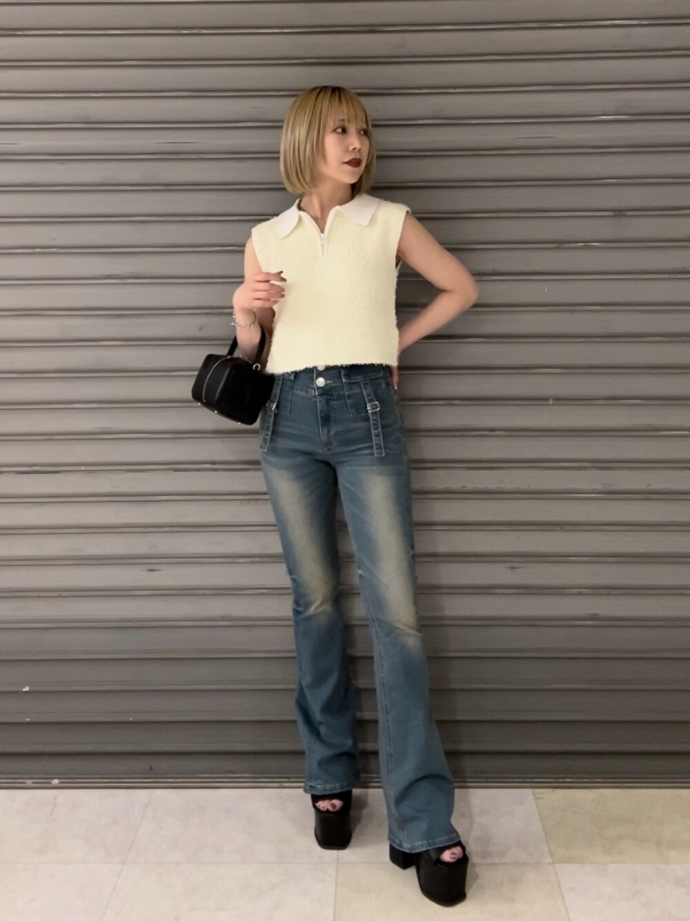 ホワイト系のタンクトップ、ブルー系のデニムパンツ、ブラック系のハンドバッグを着用したレディースの夏コーディネートの1枚目の写真