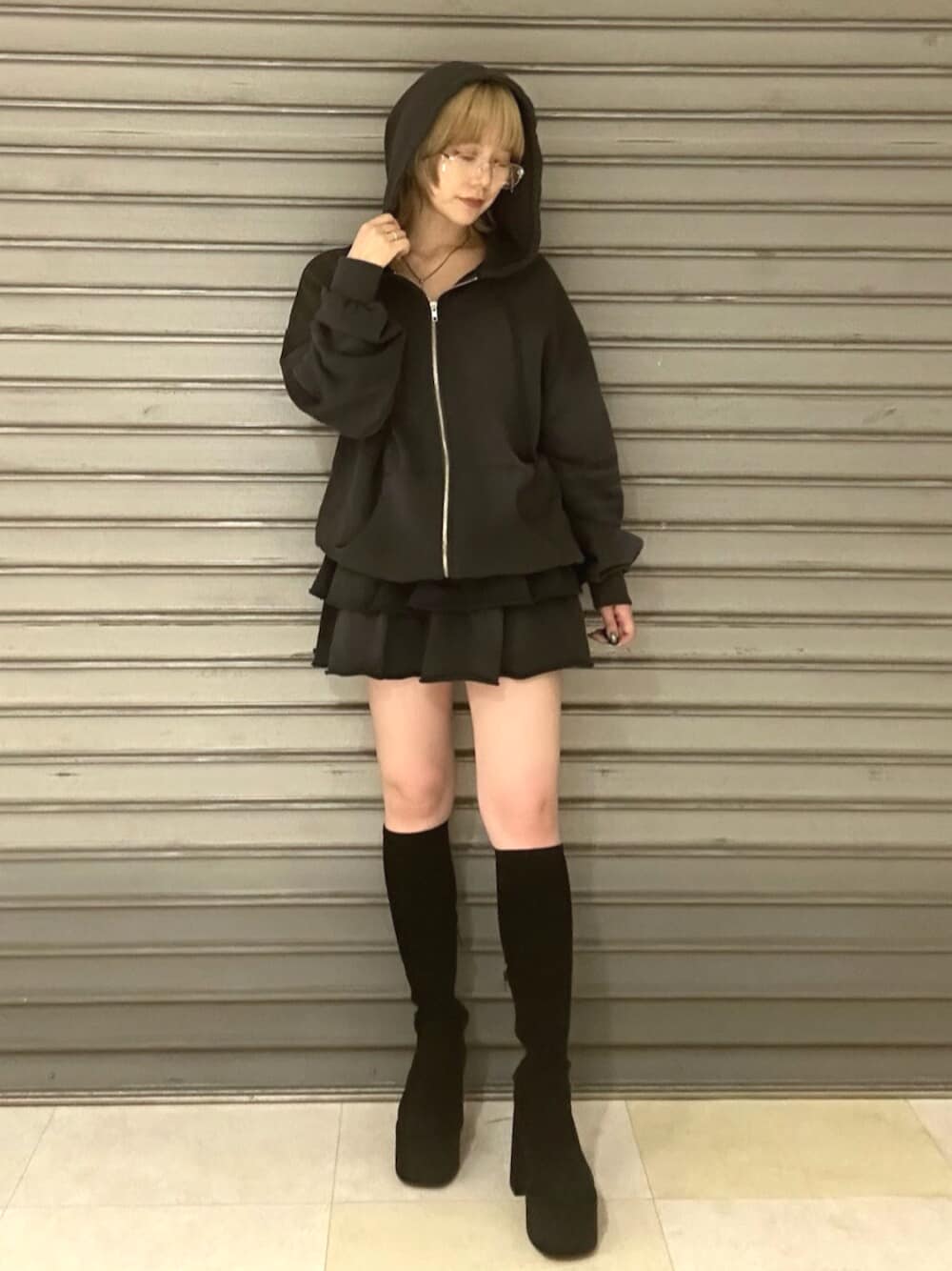 ブラック系のブーツ、グレー系のパーカー、グレー系のスカートを着用したレディースの秋コーディネートの1枚目の写真