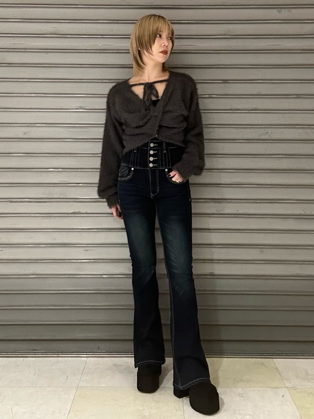 グレー系のニット/セーター、グレー系のTシャツ/カットソー、ブルー系のデニムパンツを着用したレディースの秋コーディネートの1枚目の写真