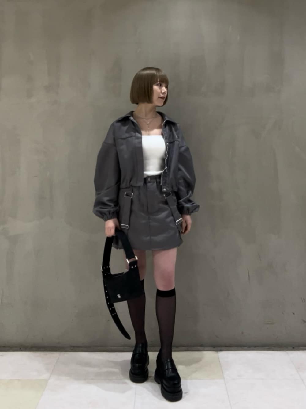 ホワイト系のキャミソール、ブラック系のショルダーバッグ、グレー系のブルゾンを着用したレディースの冬コーディネートの1枚目の写真