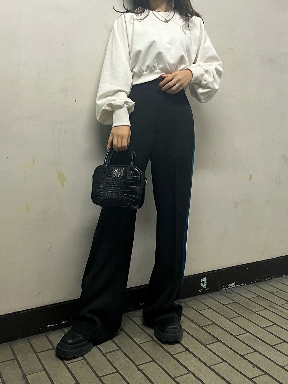 ブラック系のスラックス、ブラック系のショルダーバッグ、ホワイト系のスウェットを着用したレディースの冬コーディネートの1枚目の写真
